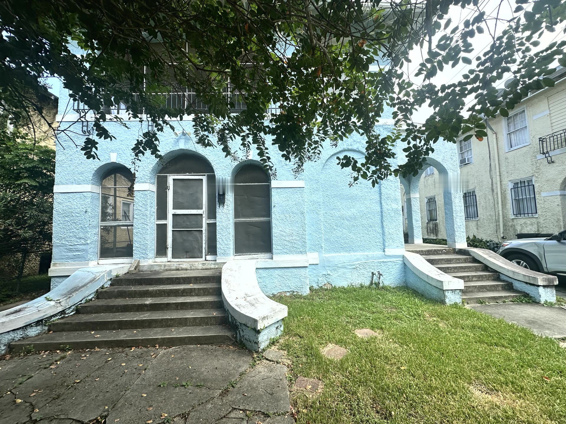 The light blue exterior of a Magnolia Haven Recovery home with arched doorways and magnolia trees